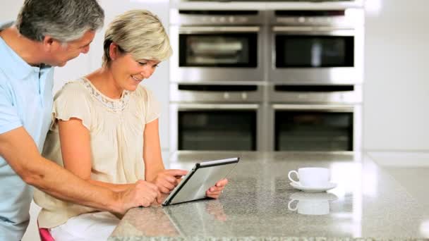 Casal caucasiano na cozinha doméstica usando tablet sem fio — Vídeo de Stock