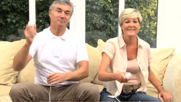 Μέσης ηλικίας ζευγάρι χρησιμοποιώντας την κονσόλα εντός έδρας αγώνες — Αρχείο Βίντεο