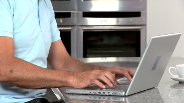 Uomo di mezza età con computer portatile sul bancone della cucina — Video Stock