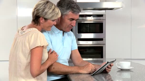 Ώριμο ζευγάρι χρησιμοποιώντας ασύρματη δισκίο στην κουζίνα — Αρχείο Βίντεο