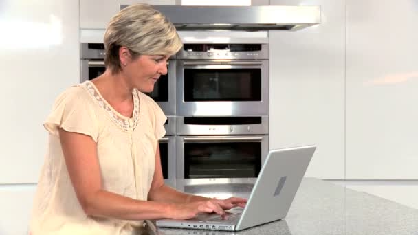 Леди средних лет с ноутбуком на кухне — стоковое видео