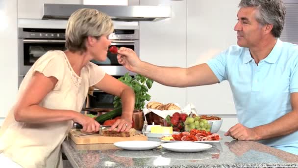 Midden leeftijd paar voorbereiding lunch in keuken — Stockvideo