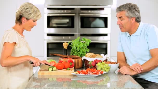 Pareja de mediana edad preparando el almuerzo en la cocina — Vídeo de stock