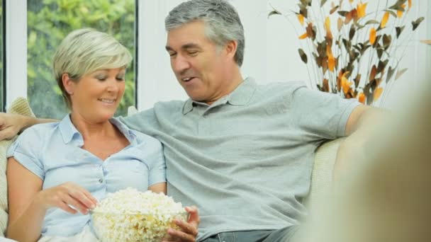 Aantrekkelijke ouder paar tv-kijken met popcorn — Stockvideo