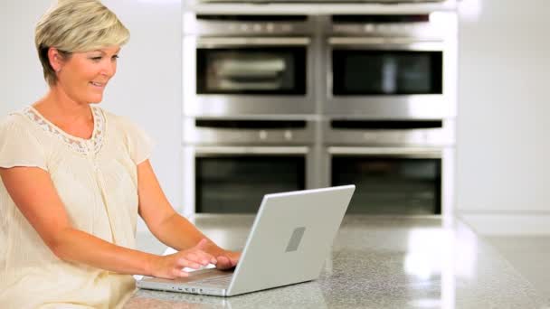 Attractive Mature Lady Working on Laptop in Kitchen — Stock Video