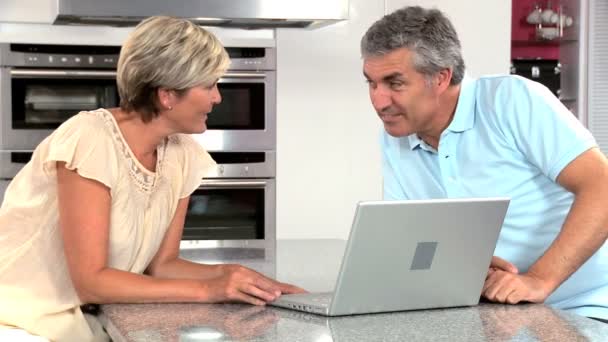 Couple mature utilisant un ordinateur portable dans la cuisine à la maison — Video