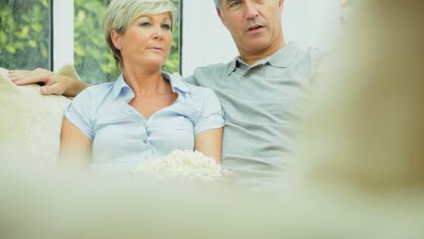 Attraente coppia matura guardando la TV con popcorn — Video Stock