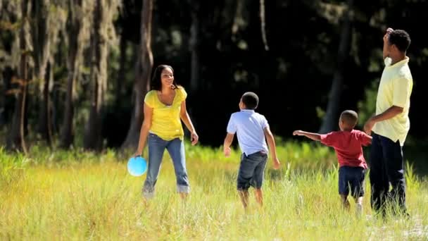 Jeune famille ethnique jouant au ballon dans le parc — Video