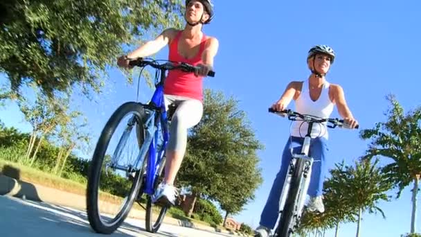 Caucásicas amigas ciclismo en las carreteras suburbanas — Vídeos de Stock