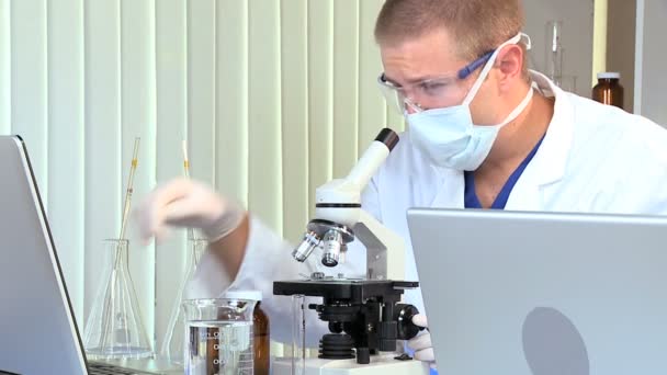 Estudiante de medicina masculino con microscopio y computadora portátil — Vídeo de stock