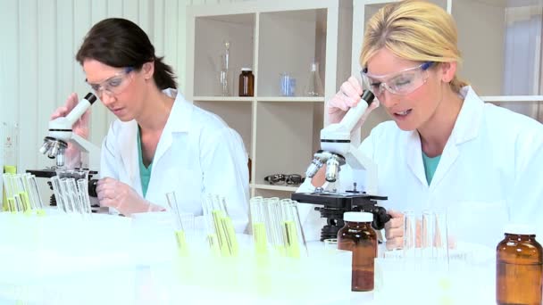 Pesquisadoras médicas femininas usando microscópios — Vídeo de Stock