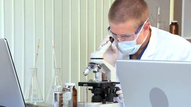 Estudiante de medicina masculino con microscopio y computadora portátil — Vídeos de Stock