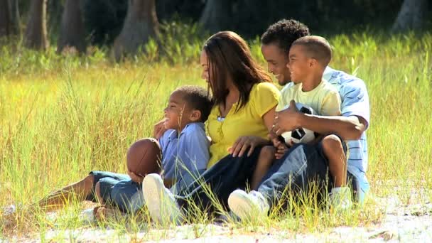 Jeune famille ethnique assise dans le parc — Video