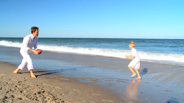 Unga far och son spelar boll på en strand — Stockvideo