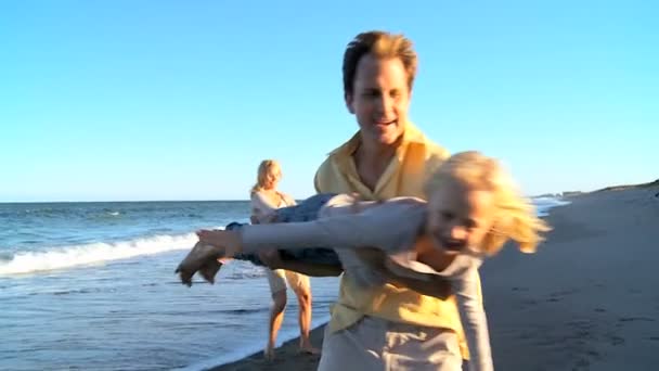 Pais caucasianos brincando com seus filhos na praia — Vídeo de Stock