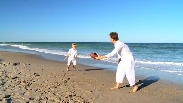 Unga far och son spelar boll på en strand — Stockvideo