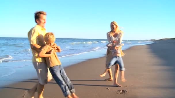 Caucásicos padres balanceando a sus hijos en la playa — Vídeos de Stock