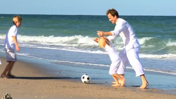 Familia caucásica pateando una pelota en la playa — Vídeos de Stock