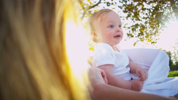 Rubia bebé con mamá divirtiéndose en el parque — Vídeos de Stock