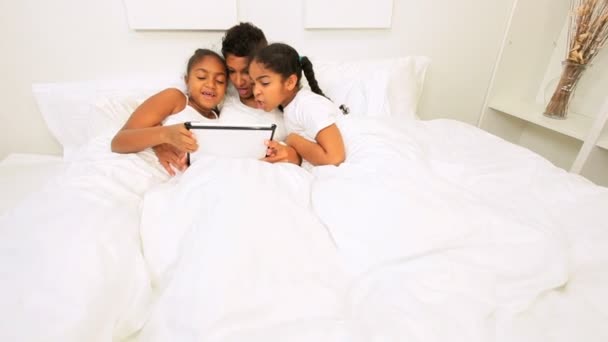 Africano americano mamá niñas cama inalámbrico tableta — Vídeos de Stock
