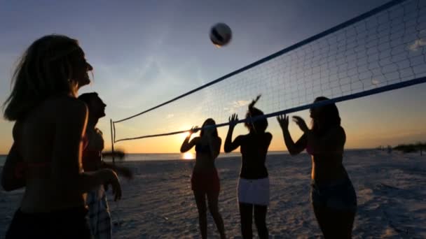 Människor på sunset spelar volleyboll — Stockvideo