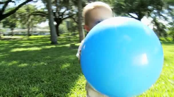 Niño feliz caminando en la hierba del parque con bola gigante — Vídeos de Stock