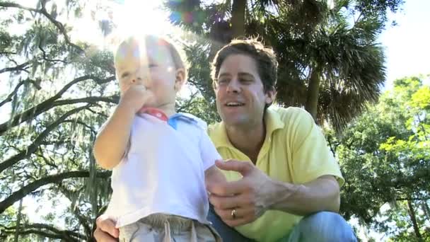 Cute Caucasian boy toddler having fun outing at park with laughing young father — Stock Video