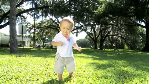 Здоровый счастливый молодой кавказский мальчик, практикующий ходьбу по траве на природе парка — стоковое видео