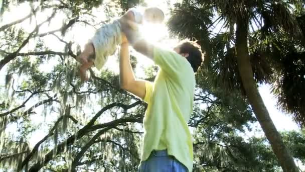 Saludable joven caucásico bebé tener diversión isheld alto en padres brazos — Vídeo de stock