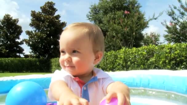 Caucasiano bebê menino se divertindo jogando na piscina bola de plástico — Vídeo de Stock
