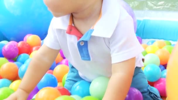 Niño feliz jugando con una pelota en la piscina llena — Vídeos de Stock