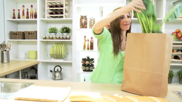 Caucasian female at home kitchen counter unpacking paper bag — Stock Video