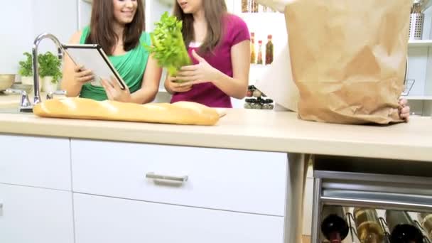 Pretty teenage Caucasian girl at  kitchen with mom and sister holding wireless tablet — Stock Video