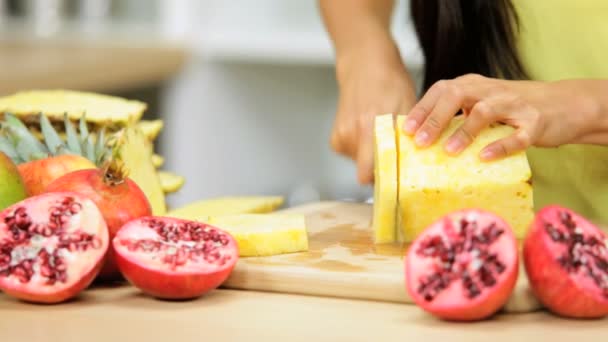 Женщина на кухне, режет ананас — стоковое видео