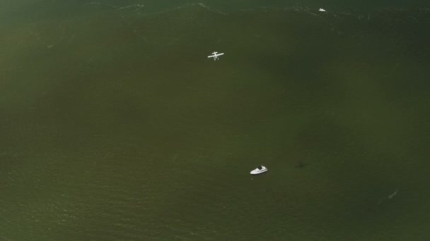 Aerial view of flying seaplane passing above cruiser, — Stock Video