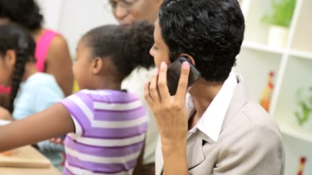 Geschäftsfrau arbeitet und telefoniert am Handy, wenn die Familie in der Küche kocht — Stockvideo