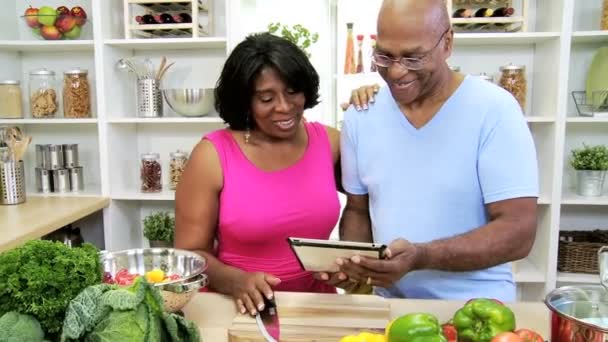 Pareja en la cocina preparando con la tableta — Vídeos de Stock