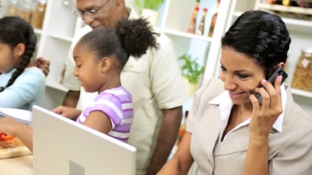 Geschäftsfrau arbeitet und telefoniert am Handy, wenn die Familie in der Küche kocht — Stockvideo