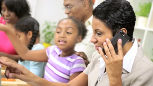 Geschäftsfrau arbeitet und telefoniert am Handy, wenn die Familie in der Küche kocht — Stockvideo