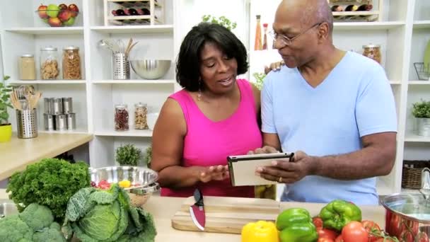 Pareja en la cocina preparando con la tableta — Vídeo de stock