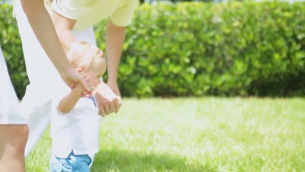 Child walking and holding parents hands — Stock Video