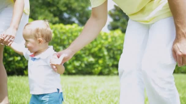 Enfant tenant de jeunes parents mains et marchant — Video