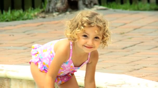Маленькая девочка, плескающаяся в бассейн — стоковое видео