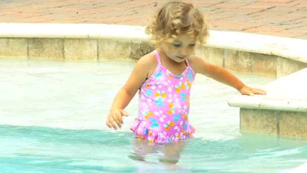 Маленькая девочка, плескающаяся в бассейн — стоковое видео