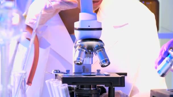 Женщина-научный сотрудник, работающая с микроскопом — стоковое видео