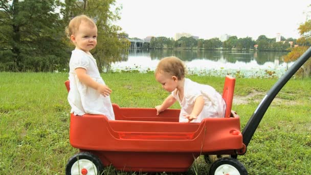 Twin girls standing in plastic cart — Stock Video