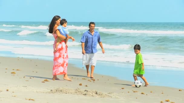 Joven familia hispana jugando al fútbol playa excursión — Vídeos de Stock