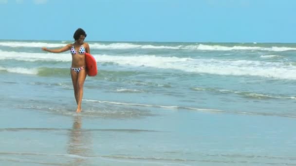 Flicka med styrelsen promenerar på stranden — Stockvideo