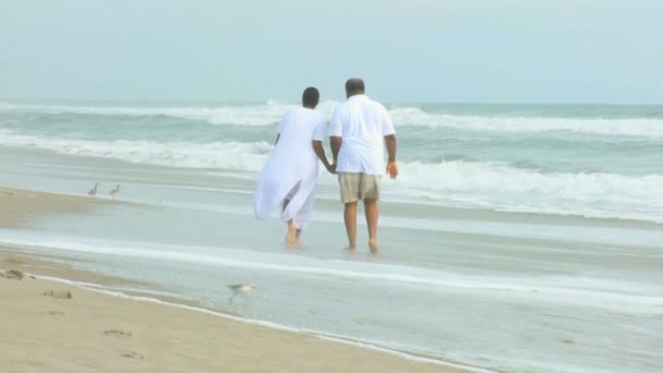 Pensionerad etniska par promenader på stranden — Stockvideo