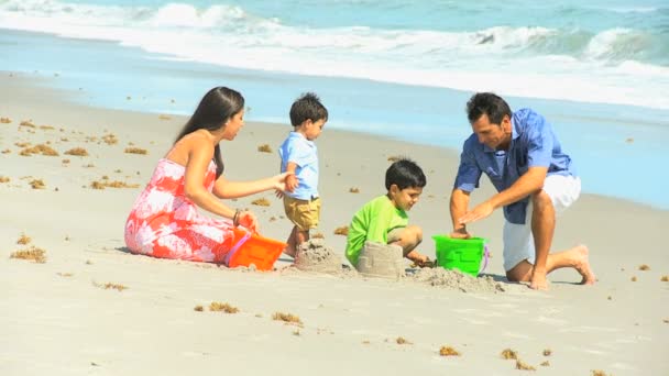 Carino ispanici fratelli making sandcastles genitori — Video Stock